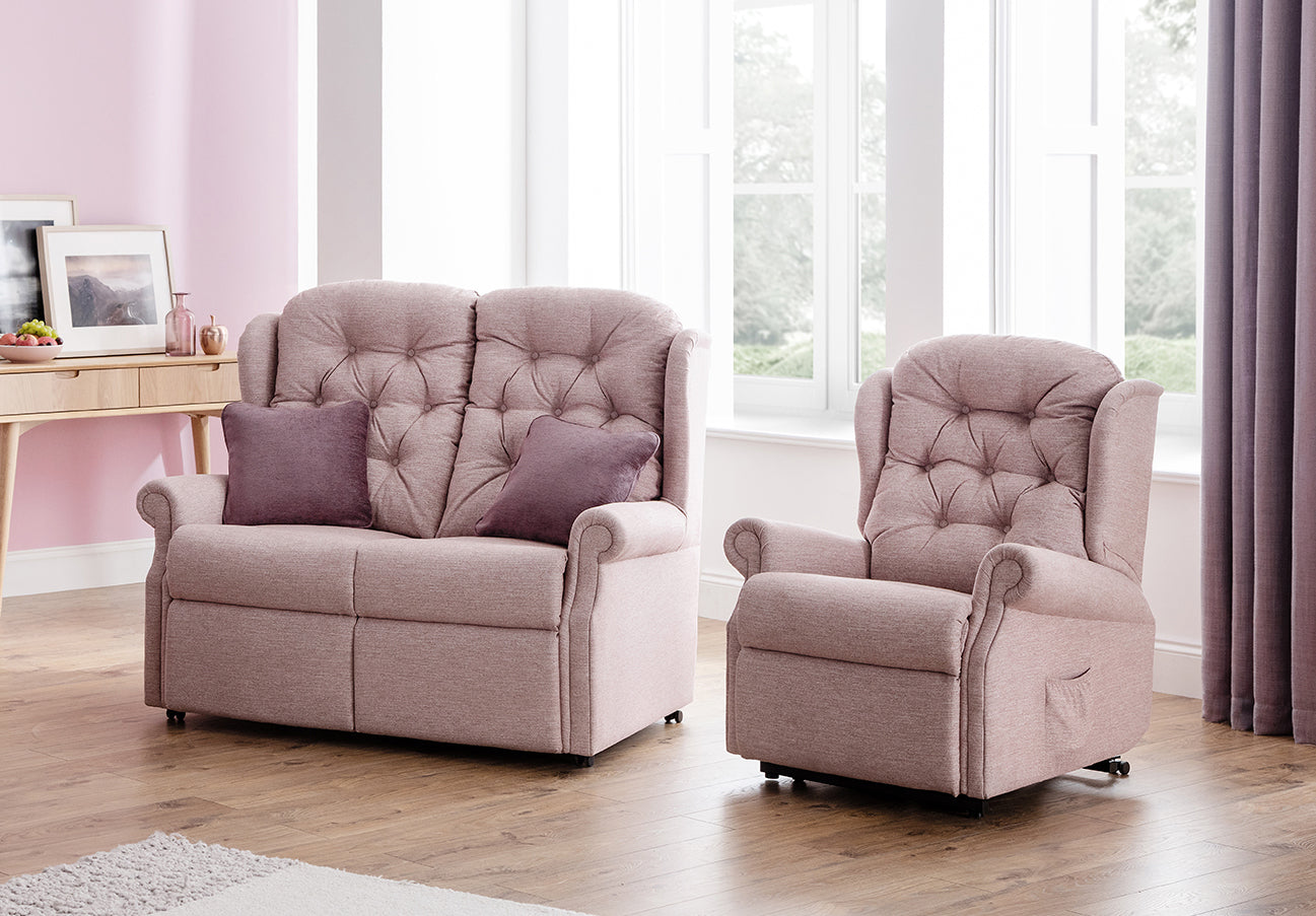 Pink sofa and armchair set in a living room with large windows.