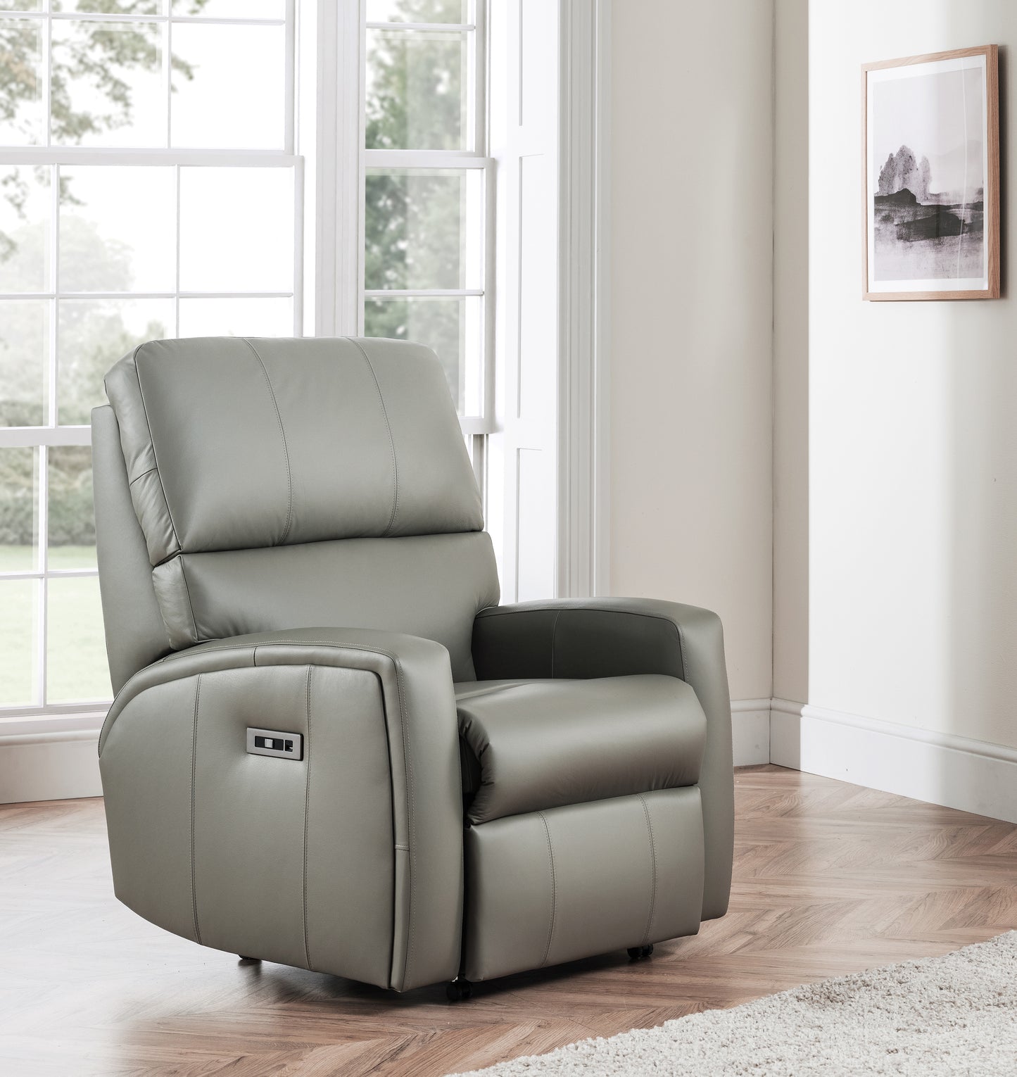 Gray celebrity southwell recliner chair in a room with large windows and a framed picture on the wall.