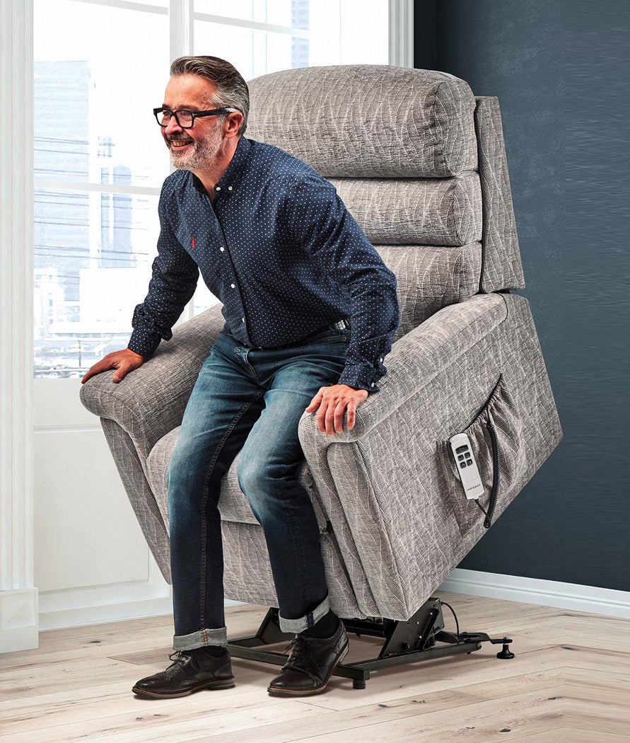 Man using a grey Sherborne riser recliner chair in a home setting