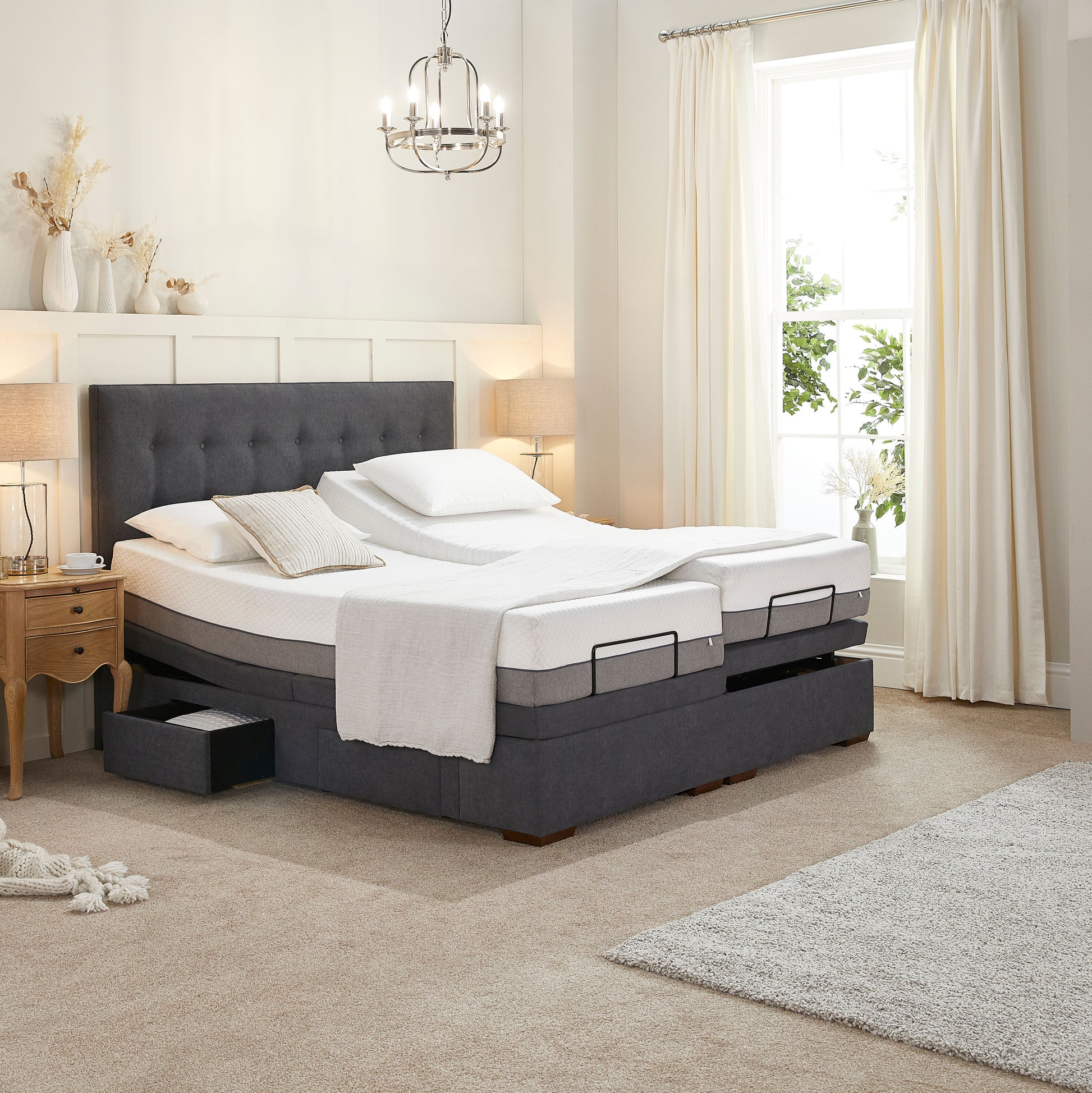 Gray adjustable bed in a bedroom setting with white bedding and pillows.