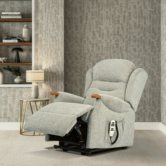 Gray recliner chair in a room with patterned wallpaper and shelves.