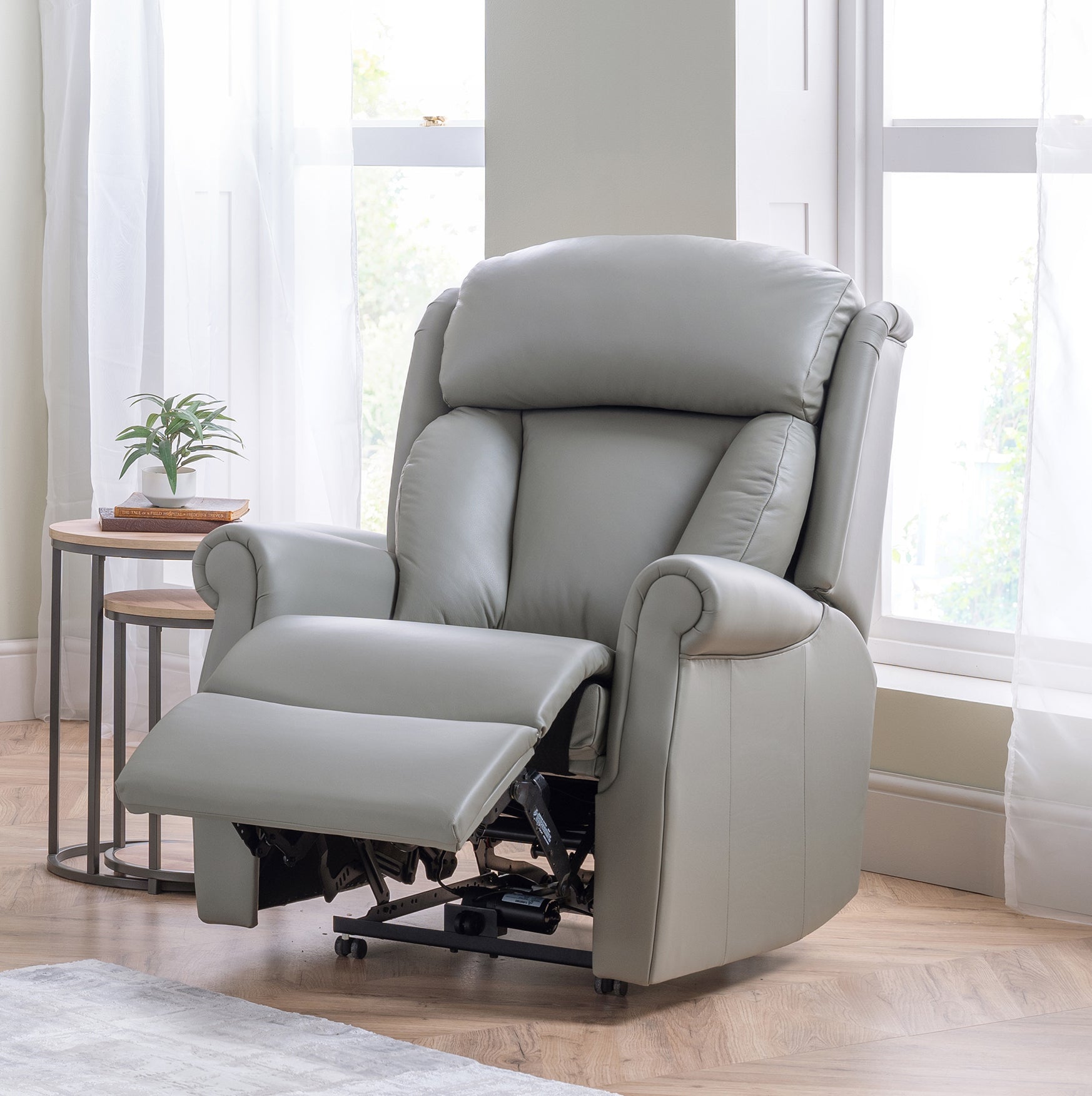 Gray celebrity riser recliner chair in a room with light wood flooring and white curtains.