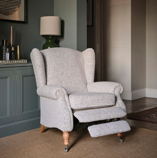 Gray patterned armchair in a room with gray walls and a lamp.