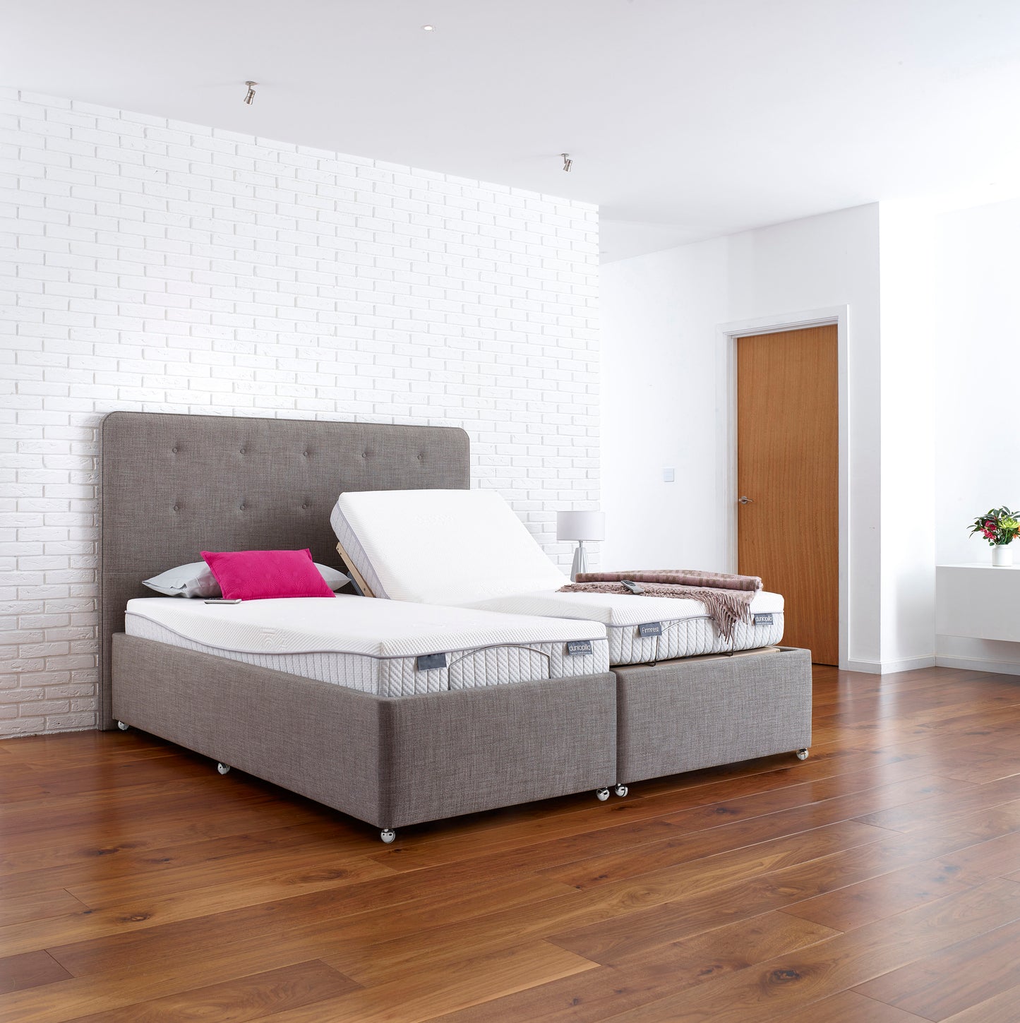 Gray adjustable bed with white mattress in a modern bedroom setting.