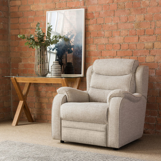 Beige armchair in a room with a brick wall, table, and decorative items.