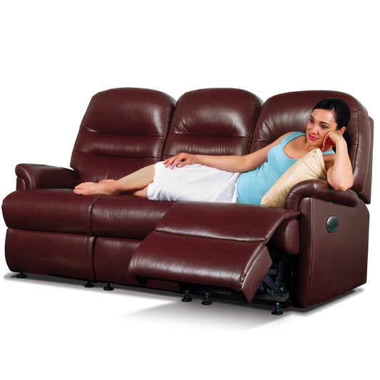 Woman relaxing on a brown leather Sherborne Keswick recliner sofa against a white background