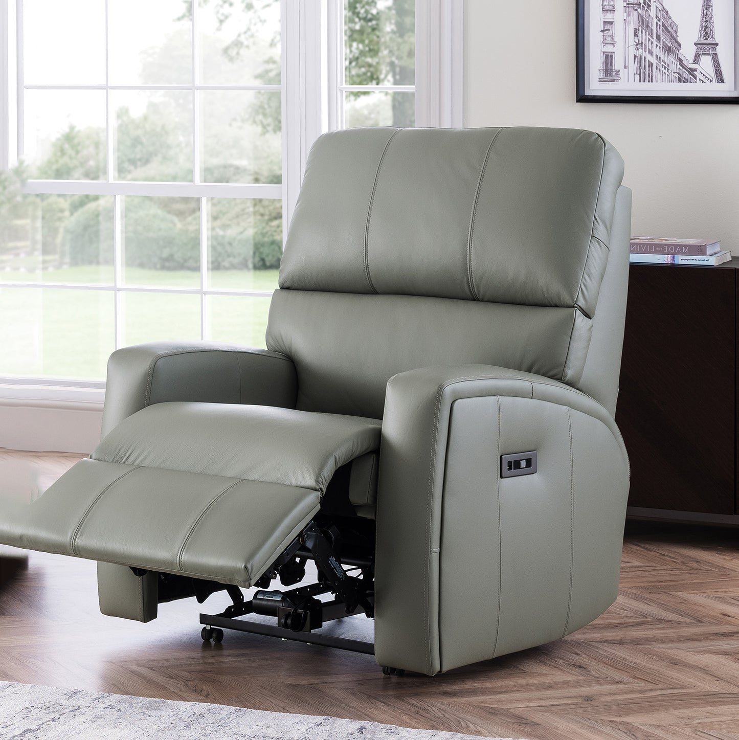 Gray celebruty southwell riser recliner chair in a room with large windows and a framed picture on the wall.