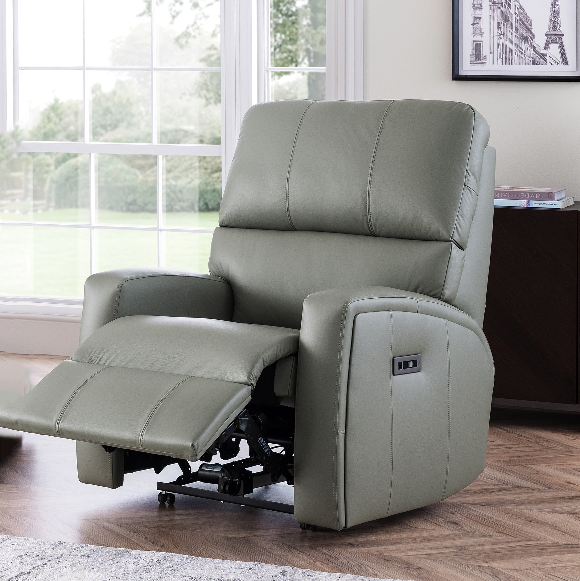 Gray celebruty southwell riser recliner chair in a room with large windows and a framed picture on the wall.