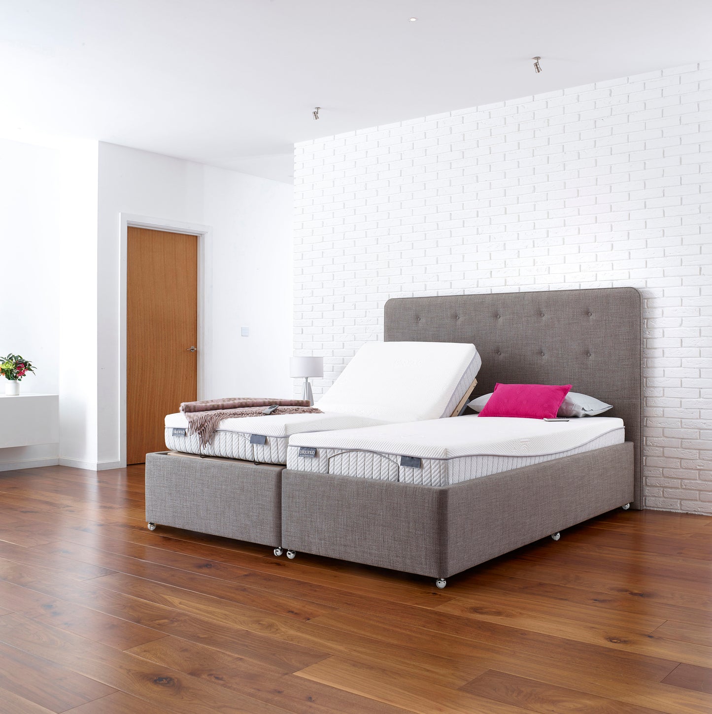 Gray upholstered bed with white mattress in a modern bedroom.